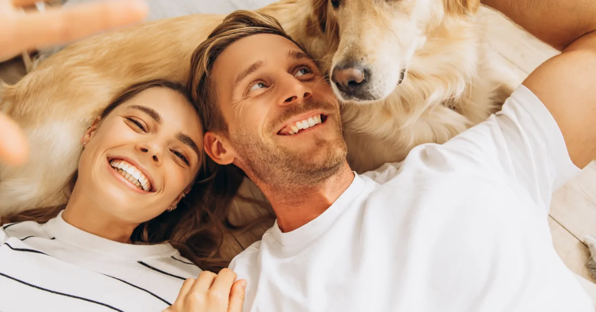 Happy couple playing with their golden retriever