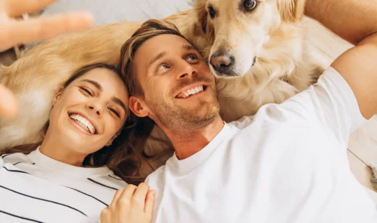 Happy couple playing with their golden retriever