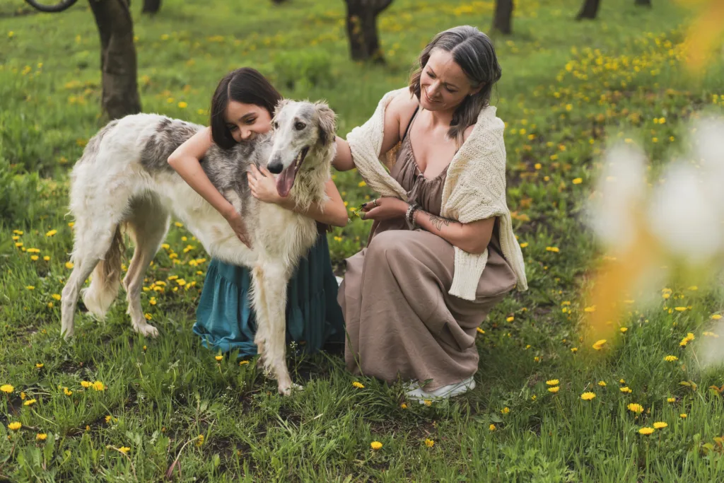 Mom and daughter hugging their pet greyhound